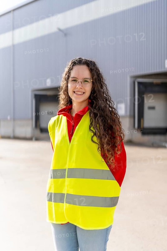 Vertical portrait of a happy young warehouse woman worker standing outside the building