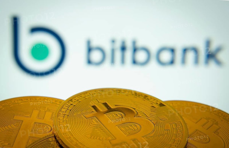 Dhaka, Bangladesh- 02 June 2025: Close-up of Bitcoin coins with the bitbank logo visible on a screen in the background