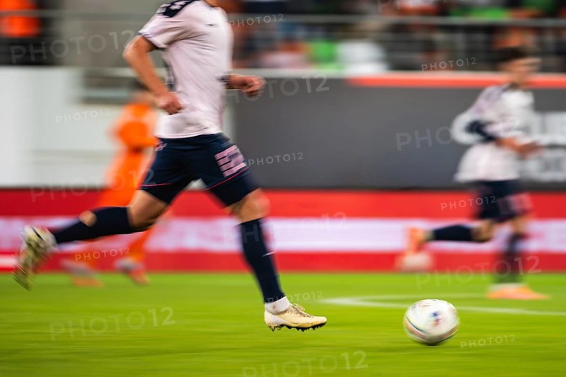 Football player runs with ball during match, blurred motion due to long exposure in Lubin, Poland