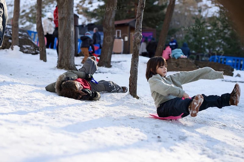 Children enjoying sledding in the snowy landscapes of Sierra Nevada Ski Resort, Granada. The scene captures their excitement and the essence of winter outdoor fun