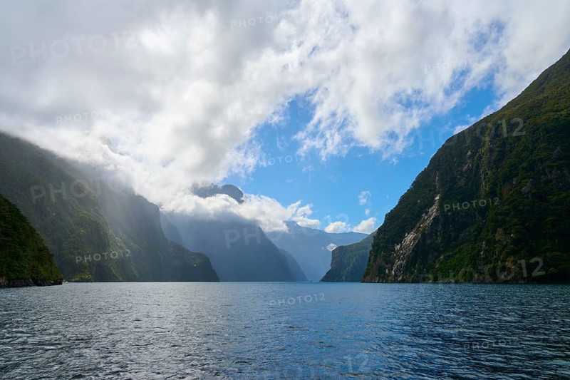 Wide fjord with steep, forested slopes and dramatic cloud formations in the sky, summer, Milford Sound, Te Anau, Fiordland National Park, South Island, New Zealand