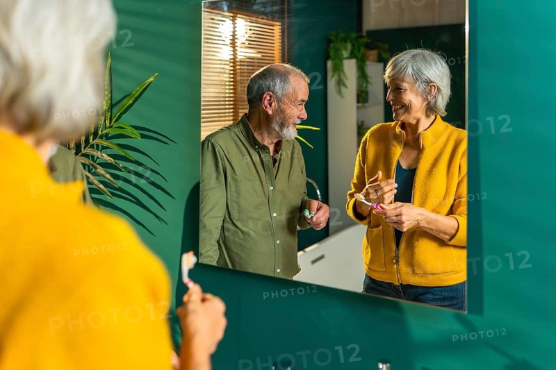 Reflection on the mirror of a caucasian senior couple washing teeth together at home