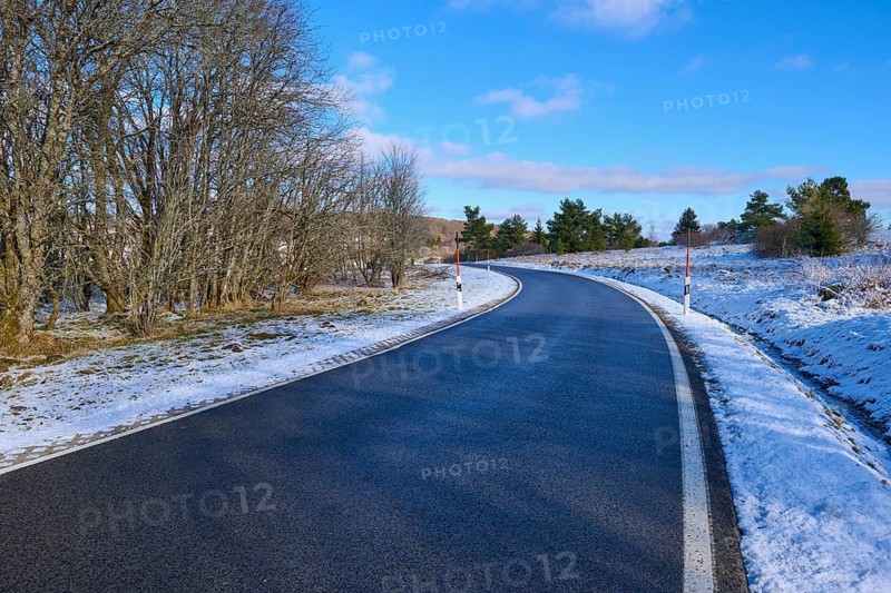 A winding road leads through a snow-covered landscape with trees and a clear blue sky, winter, Oberelsbach, Lange Rhön, Rhön, Bavaria, Germany
