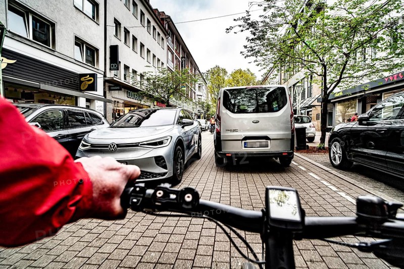 Cycling in the city, inner-city street, cycle lane, bicycles have priority, two-lane traffic with parked cars on both sides, cyclists' perspective, Essen, North Rhine-Westphalia, Germany