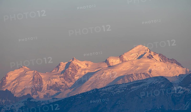 A breathtaking sunset casts a warm glow over the Swiss and French Alps, as seen from Geneva