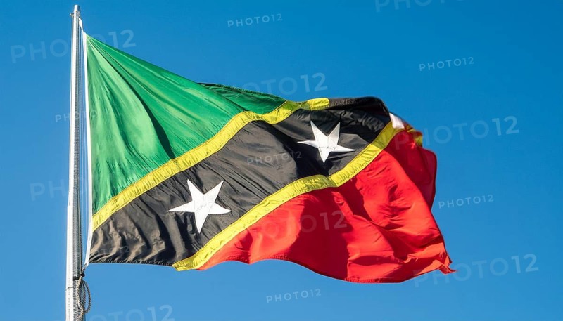 The flag of St Kitts, Caribbean, fluttering in the wind, isolated against a blue sky