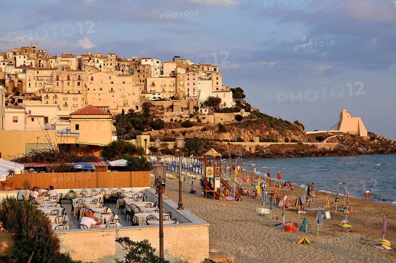Terrace of a Ristorante Pizzeria at the beach Lido di Fondi, rocky outcrop with historic fortress Torre Truglia, Tyrrhenian Sea, warm evening light at sunset, old town, Sperlonga, Latina, Lazio, Italy