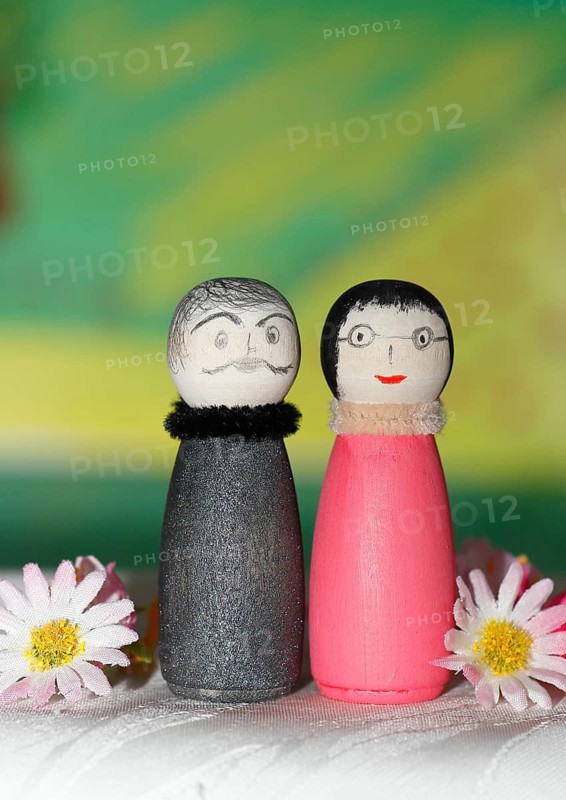 Funny painted wooden cone man and woman in front of a colourful painted background, North Rhine-Westphalia, Germany