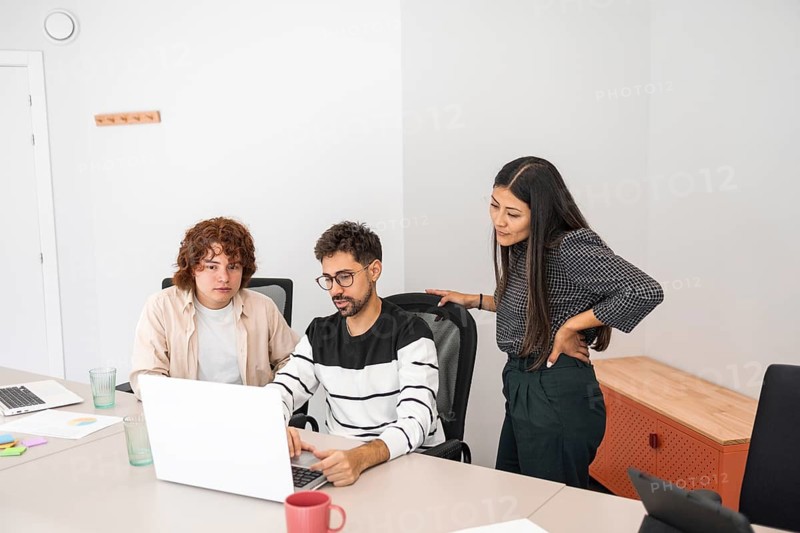 Diverse coworkers engage in collaborative work at a modern office A team of professionals discusses a project, emphasizing cooperation, creativity, and problem-solving