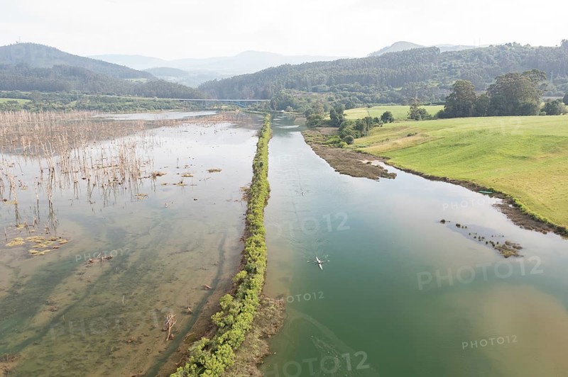 Aerial view of a serene river winding through lush wetlands and green fields near San Vicente de la Barquera, Cantabria, Spain, highlighting natureâ€™s tranquility and beauty