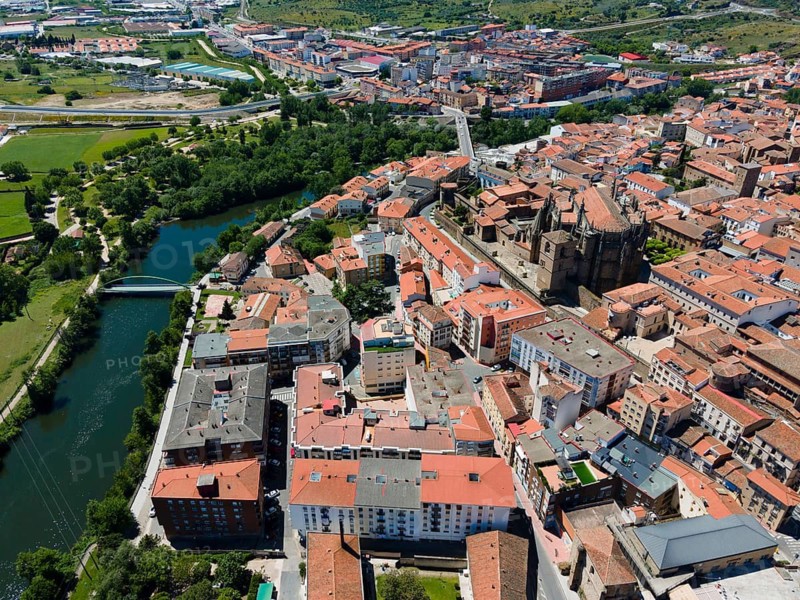 Aerial view of a town with red tiled roofs, river, bridge and green trees on a sunny day, aerial view, Plasencia, Jerte River, Cáceres, Caceres, Extremadura, Spain