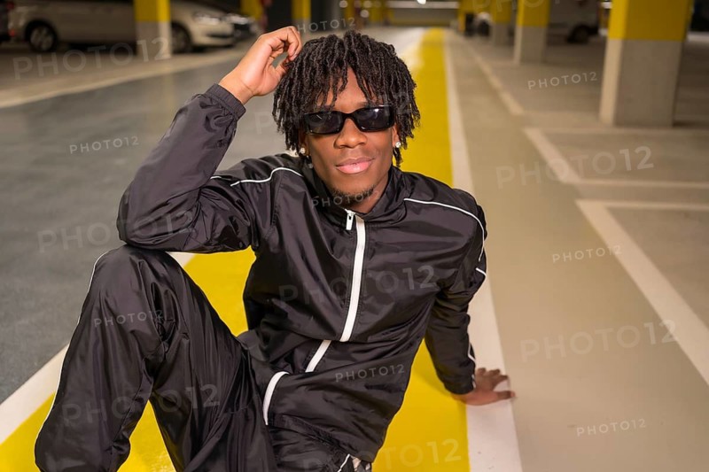 Modern musician sitting posing on a garage smiling at camera