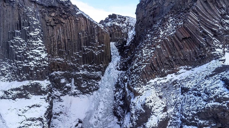 The beautiful Hengifoss waterfall frozen in the cold winter of Iceland, volcanic cliffs