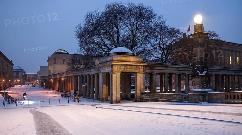 A cyclist rides over snow-covered streets at the old National Gallery in the early morning, Berlin, 13/02/2025, Berlin, Berlin, Germany