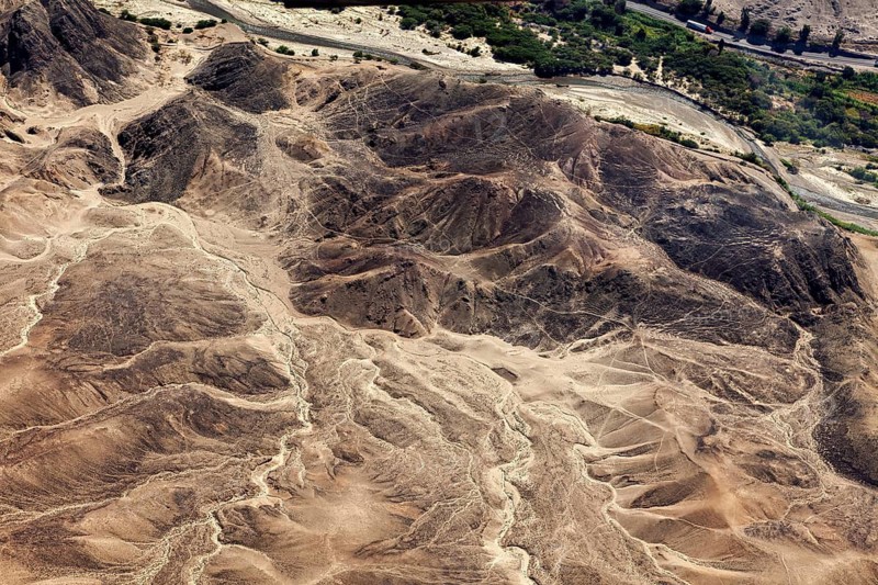 Aerial view of a desert landscape with hills, a river course and sparse vegetation, The landscape and desert near Nasca in the Andes of Peru