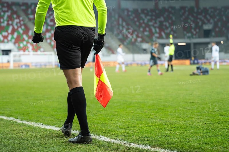 Assistant of football referee during the match. In the background main referee gives yellow card