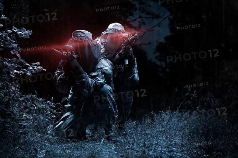 Two fighters of a special unit move through the forest at night. The concept of special operations, NATO, war.