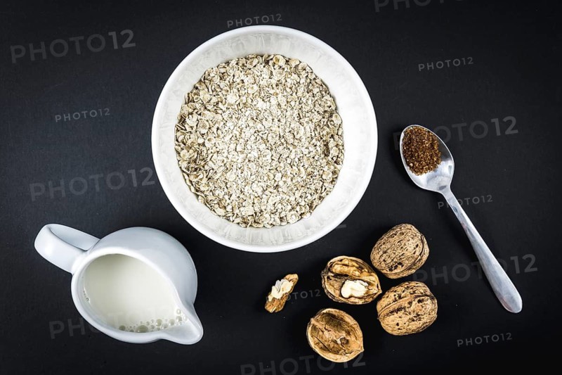 Oatmeal in a cup and winged walnuts, milk and sugar. Oatmeal recipe with walnuts, prunes, cinnamon and sugar