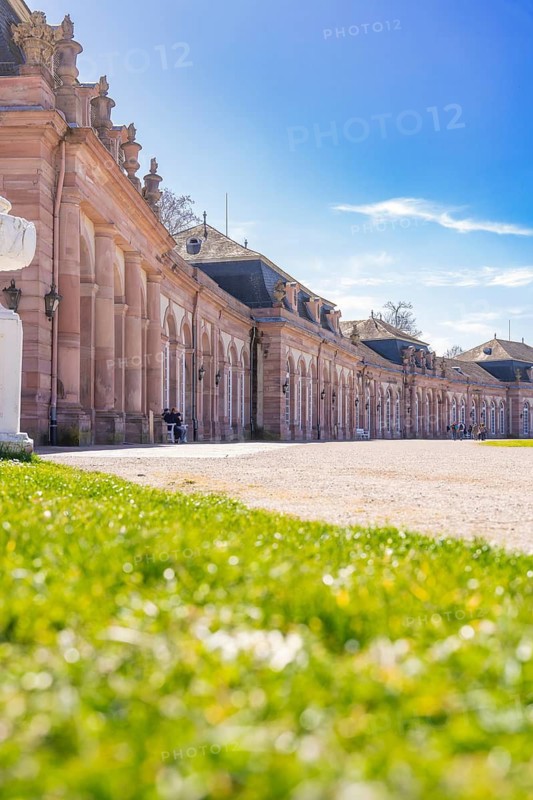 Baroque building with blue sky and green meadow in the foreground, Schwetzingen Palace Gardens, Germany