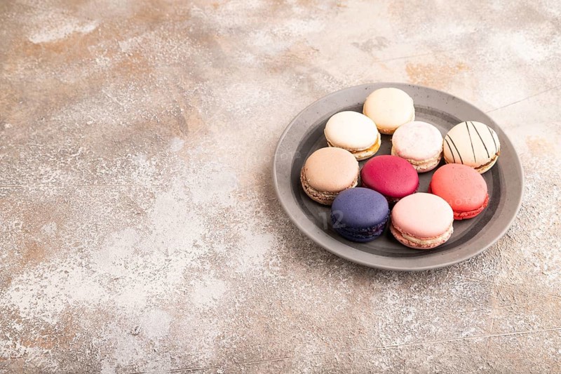 Macarons colourful cookies dessert, on brown concrete background, copy space, side view