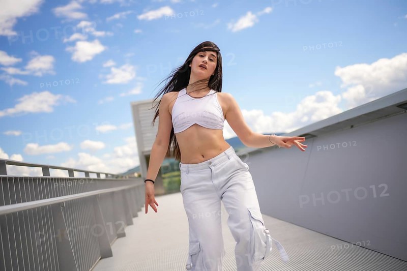 Energetic female caucasian casual dancer performing urban choreography on a bridge in a sunny day