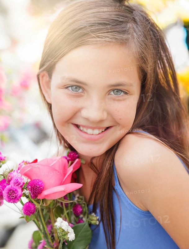 Adorable happy young blue eyed girl holding a fresh cut floral bouquet at the farmers market