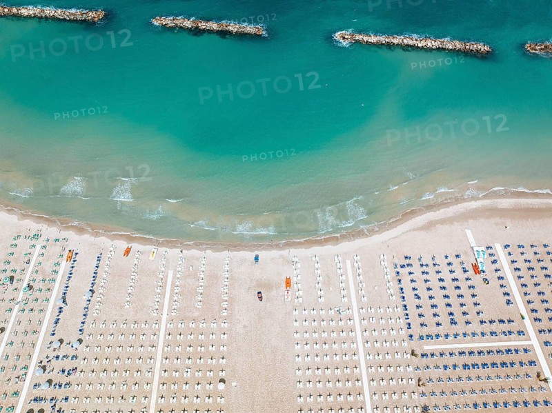 Stunning aerial perspective of San Benedetto beach, featuring rows of sun loungers and vibrant turquoise waters, embodying Italian coastal beauty