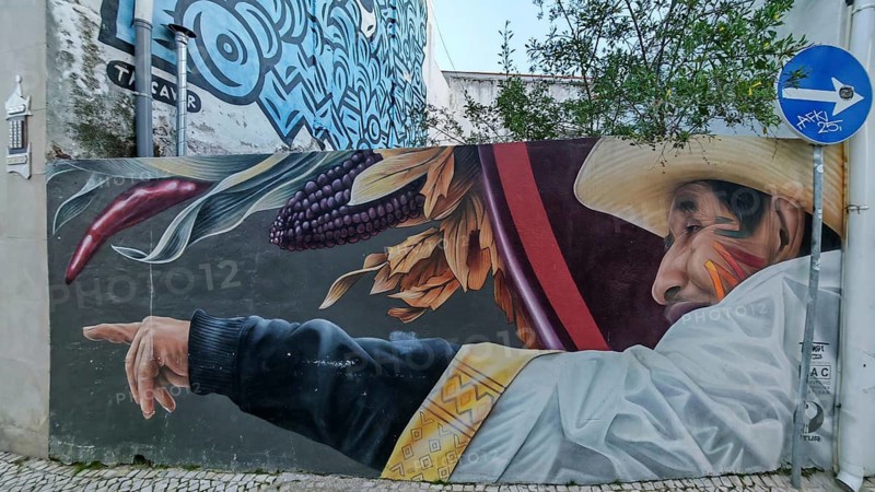 Street art, large wall mural, Moon over Matatlan, image of a Mexican man wearing traditional clothing with dynamic colors, Lagos, Algarve, Portugal