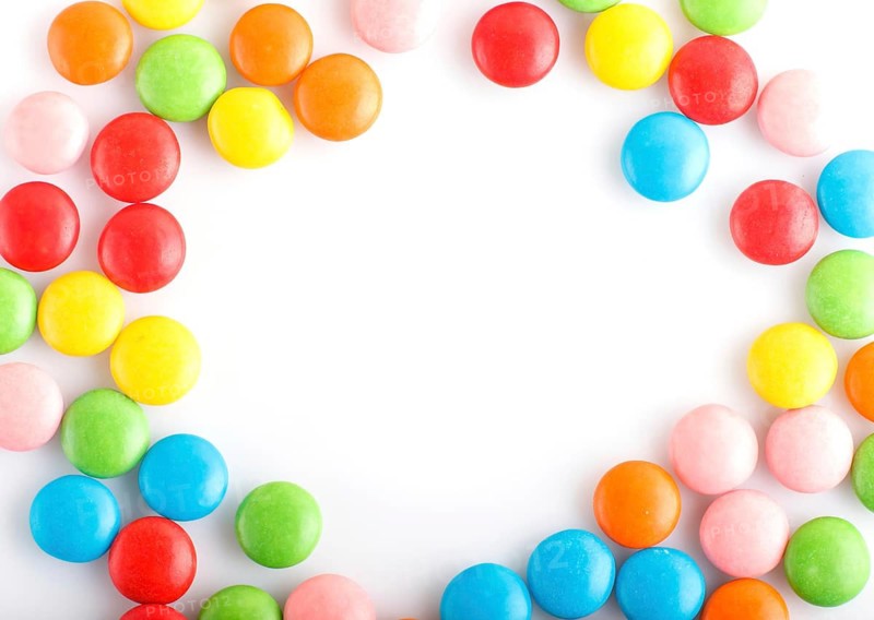 Colorful frame of multicolored chocolate candy dragees isolated on white background. Copy space. Top view