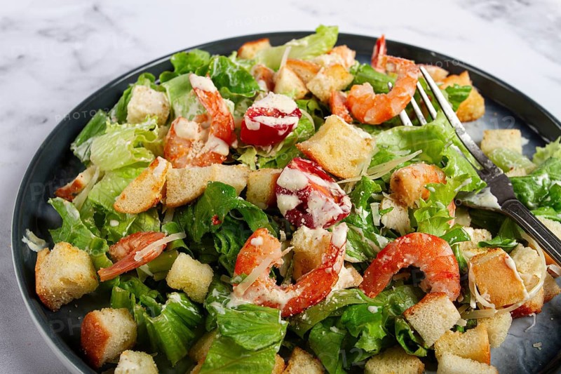 Caesar salad, with shrimp, on a marble background, top view, no people