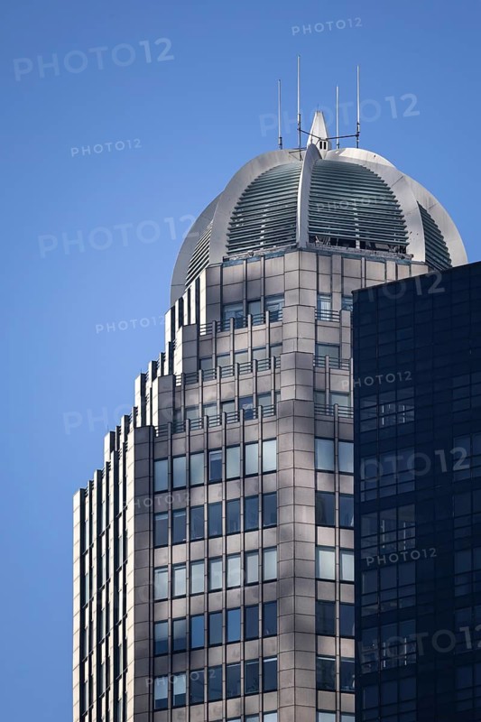 A close-up view of a modern skyscraper in New York featuring a unique circular rooftop with metal details under a clear blue sky