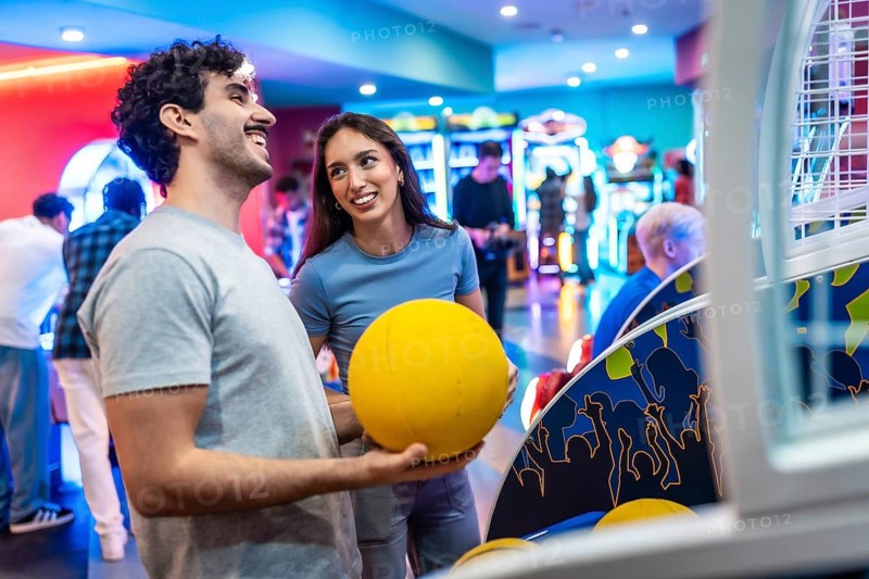 Young multiethnic couple having fun playing arcade basketball together, enjoying their weekend leisure time in an entertainment center