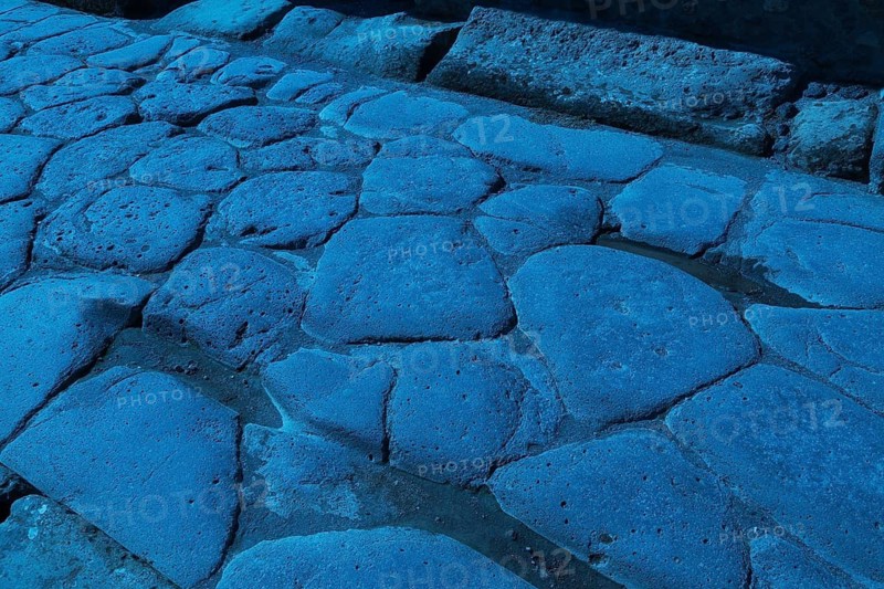 Close-up of large grey smooth and worn lava stones in a street at the ancient ruins of Pompeii, Campania region, Italy