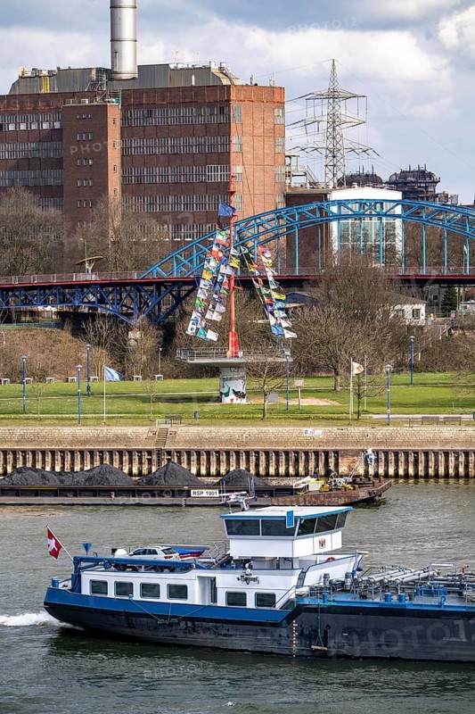 Cargo ships at the Mühlenweide, flagpole, on the Rhine, Ruhrort harbour, in the background the Hermann Wenzel gas-fired power station, ThyssenKrupp Steel, Duisburg, North Rhine-Westphalia, Germany