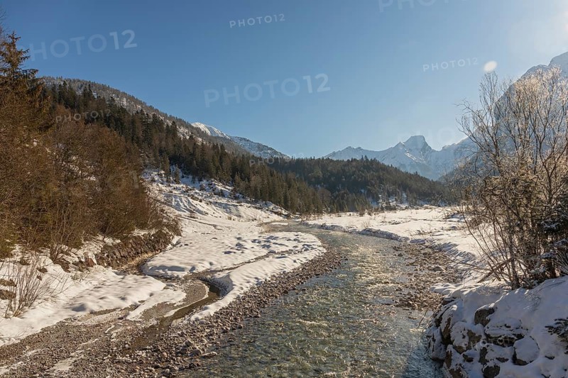 The Riss creek flowing through a snow covered landscape in the Eng valley. Sunny day with blue sky