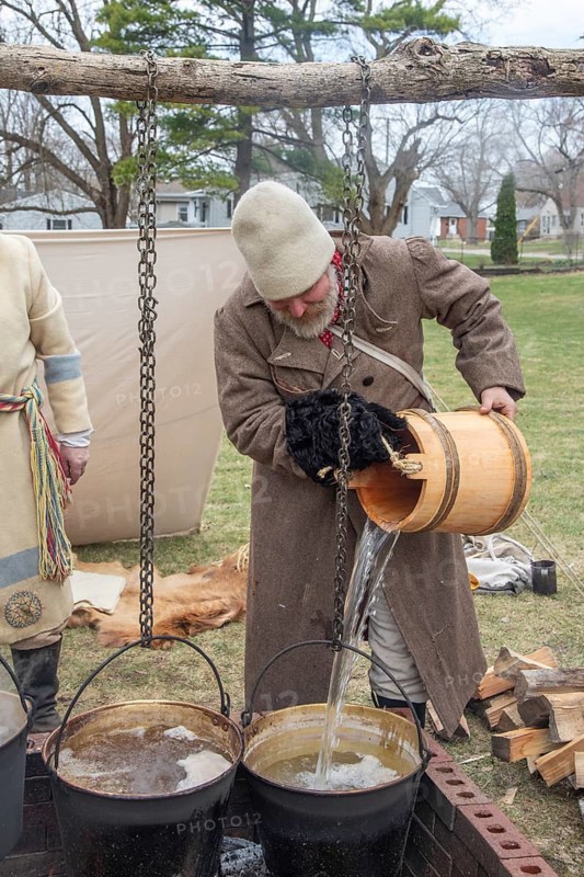 Monroe, Michigan - Workers from the Monroe County Museum demonstrate maple sugaring as it was done in the early 1800s. Raw sap, which contains only 2 percent sugar, is poured into a bucket on the fire