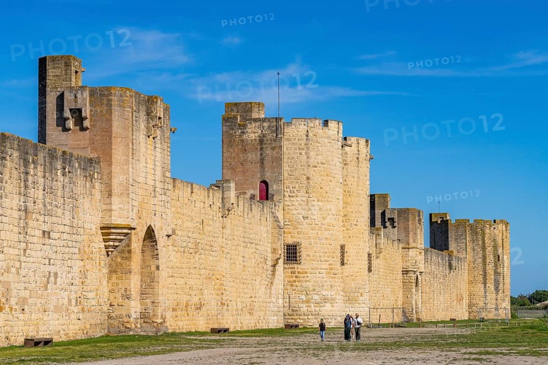 Walkers in front of defensive towers and city walls from the Middle Ages, Aigues-Mortes, Camargue, Provence, France