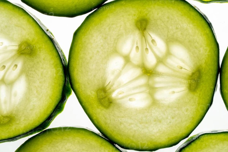 High resolution image showcasing a close up view of fresh cucumber slices, highlighting their vibrant green color, texture, and seeds against a bright background