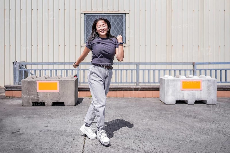 Asian woman jumping dancing k-pop urban dance alone outdoors in an industrial parking