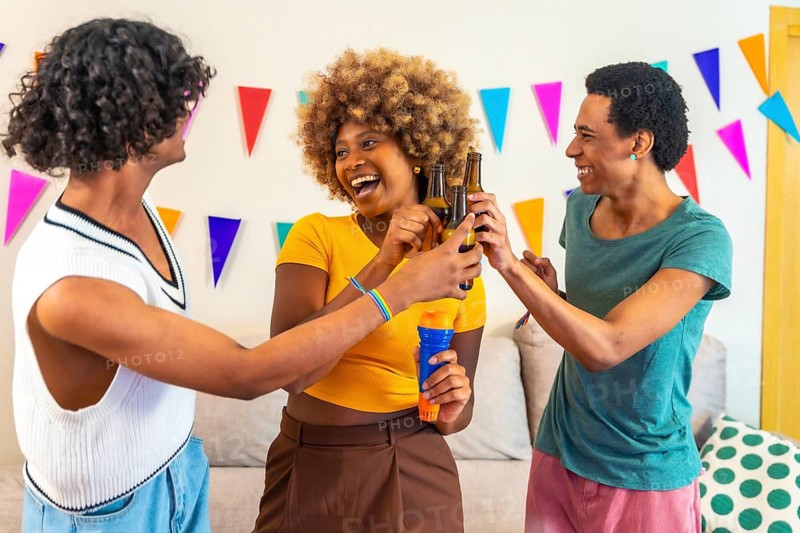 Multi-ethnic friends having fun toasting with beer and singing in a karaoke party at home