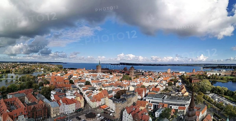 Coastal town with old town roofs and views of the sea under a partly dramatically cloudy sky, view over Szczecin, Poland