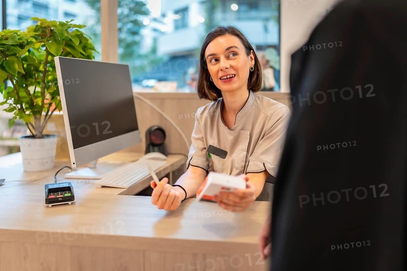 Female young pharmacist attending and talking with a client in the counter of the store