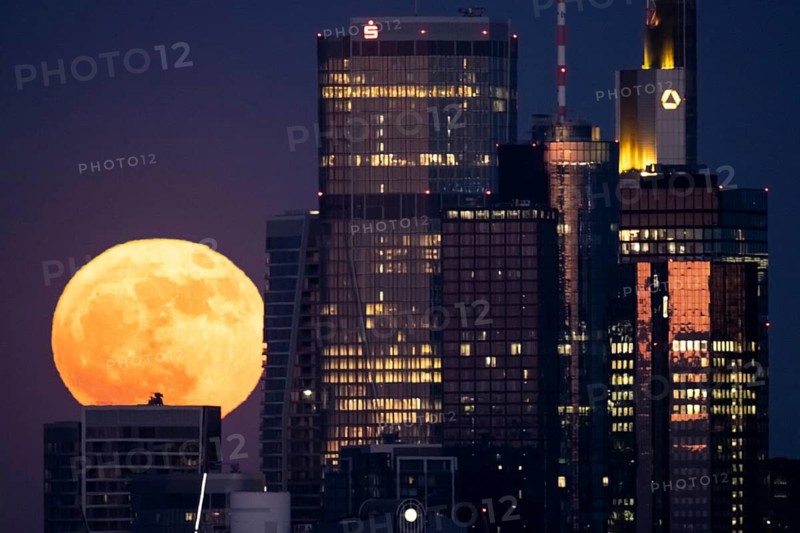 The full moon passes behind the Frankfurt banking skyline, Frankfurt am Main, Hesse, Germany