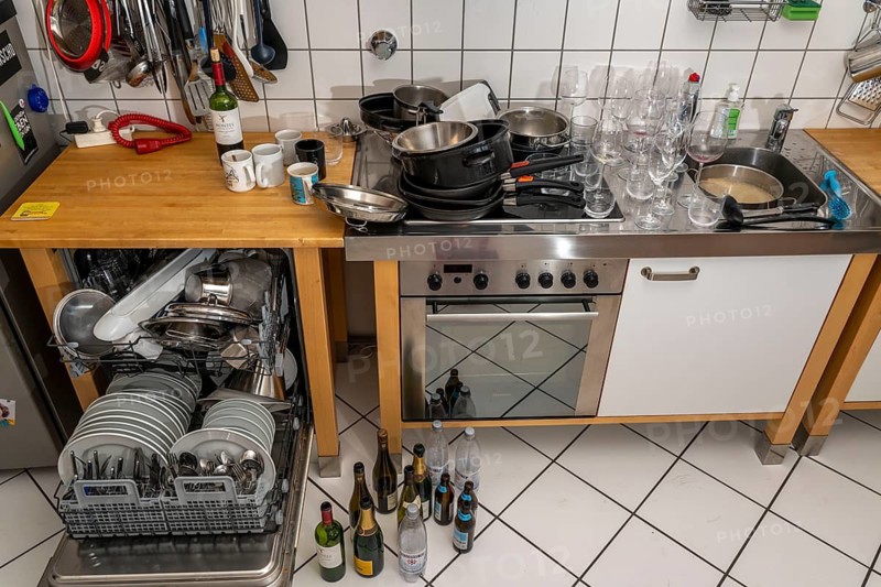 Kitchen after a big dinner, cooking party, dishwasher, full, with cleaned dishes, dirty glasses, pots, cooking utensils on the sink, waiting to be washed