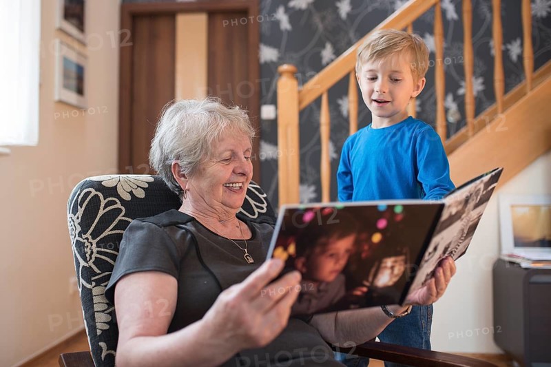 Grandmother and grandson watching photo album with the grandson pictures on the cover