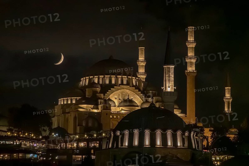 Istanbul's Suleymaniye Mosque, aglow with warm lights under a crescent moon, exemplifies majestic Ottoman architecture and atmospheric nights in the city