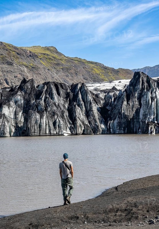 Tourist at the lakeside of a glacier lagoon, glacier tongue with crevasses and lake, Sólheimajökull, South Iceland, Iceland