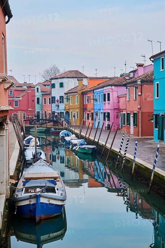 Colorful houses beside the waterway in between 'Riva dei Santi' and 'Fondamenta di Terranova' with boats lying in the water on the island of Burano, Italy