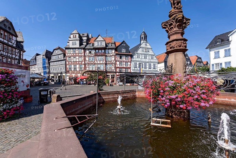 Kump, medieval market fountain with geraniums, decor, row of houses, half-timbered houses Gasthaus Zum Goldenen Löwen and Old Town Hall, market square, market, pedestrian zone, historic old town, Butzbach, Wetterau, Hesse, Germany