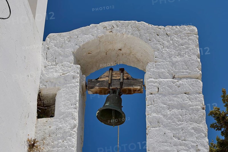 Taxiarchis, Church of the Archangel, close-up of a bell under a stone arch against a blue sky, Megalo Chorio, Zero Waste Island, Tilos, Dodecanese, Greek Islands, Greece